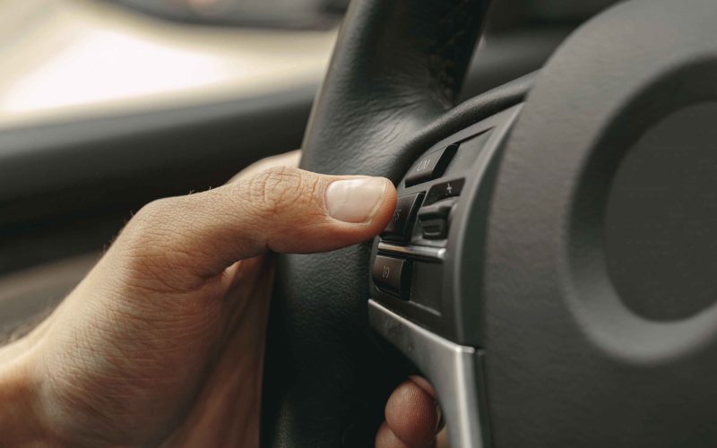 Close up picture of driver hand pushing the button of media control button in steering wheel